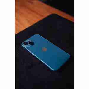 Photo by Douglas Mendes Blue smartphone on a dark surface with wooden table, emphasizing modern technology and design.